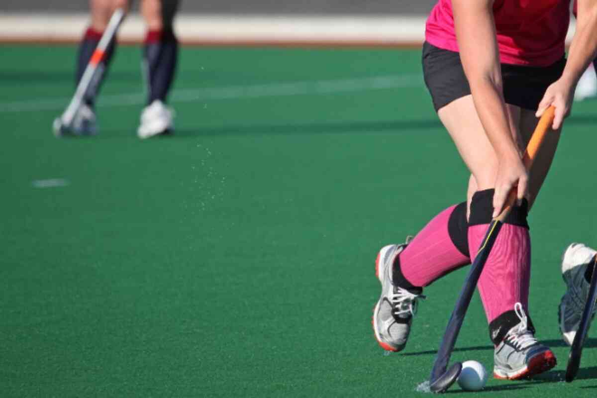 Hóquei esportivo e mulher em ação no campo com taco de hóquei pronto para  bater a bola no jogo exercício de fitness e atleta feminina jogando hóquei  em campo no estádio ao